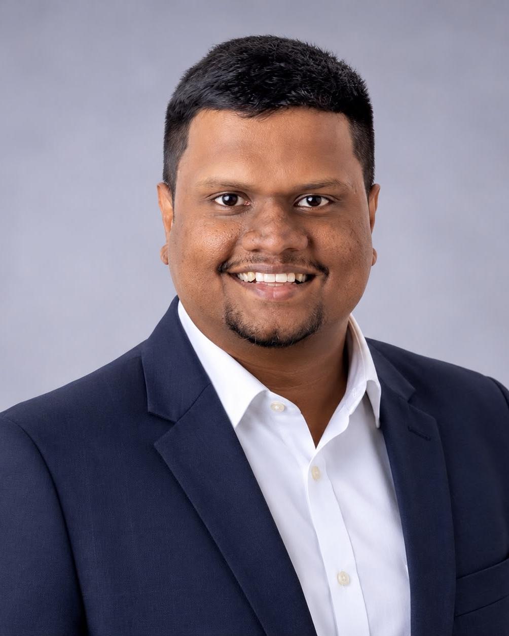Portrait of Dulan Dias in a navy jacket and white shirt